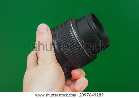 lens 18-55 mm for a camera in a man's hand on a green background