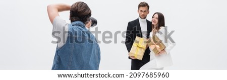 back view of photographer taking photo of stylish models with gift boxes isolated on white, banner