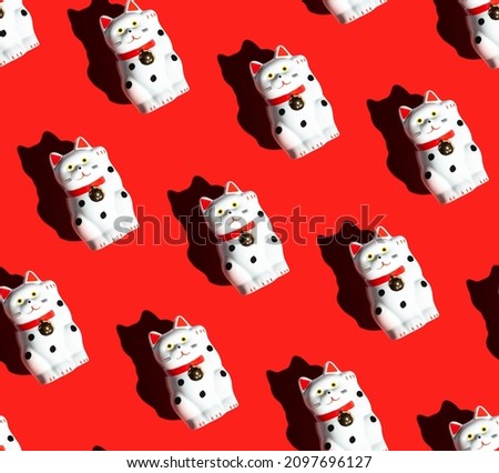 seamless pattern of maneki-neko cats on a red background. Beckoning cat. The lucky cat's right paw is raised. Royalty-Free Stock Photo #2097696127