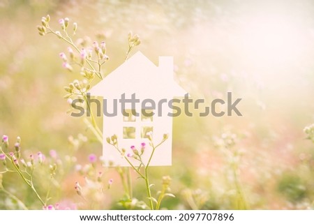 white paper house on grass flower in morning garden.homeless housing and home protection insurance concept, international day of families, foster home care, family, and real estate. Royalty-Free Stock Photo #2097707896