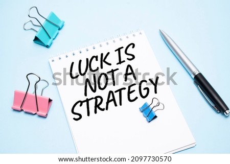 White notepad with text Luck is not A Strategy and office tools on the blue backgroundd