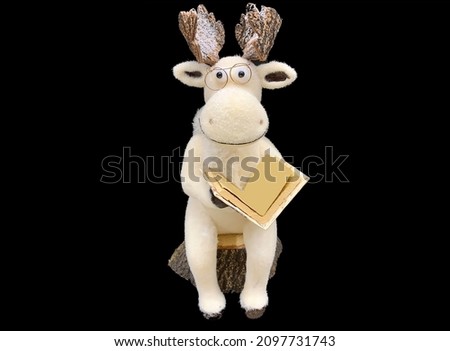 New Year's soft toy - a deer with horns. A doll with a book decor under the Christmas tree. Christmas gift to children, isolated on black.