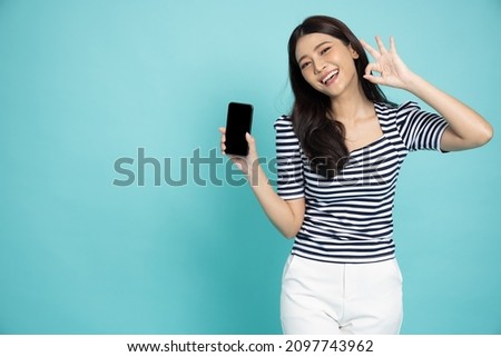 Portrait of Asian woman showing or presenting mobile phone application and ok sign isolated over green background, Asian Thai model