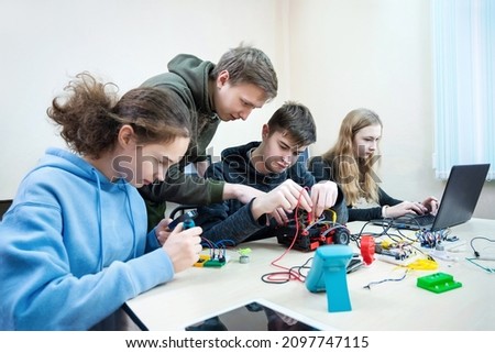 Diverse teenager pupils build robot vehicle learning at table at STEM engineering science education class. Royalty-Free Stock Photo #2097747115