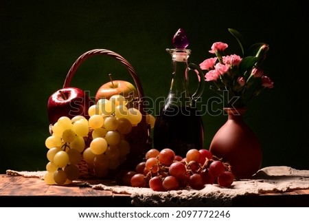 Picture with wine in the background. Still life with fresh fruits such as red and white grapes, apples, tangerines, clementines and lime with a bouquet of cloves. A composition for a desktop 