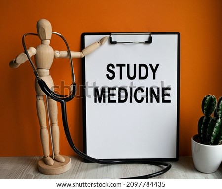 Medical table with a wooden person along with a stethoscope. Inscription STUDY MEDICINE on the clipboard with the holder. Health care concept.