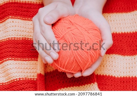 red skein of wool in hands on a yellow-red tablecloth. High quality photo