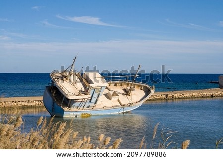 An old ship, thrown onto the beach, lies on its side.