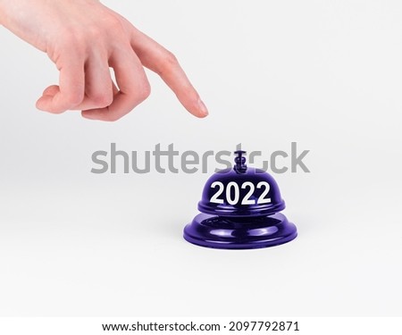 2022 New Year start concept. Hand finger pressing desk bell button.
