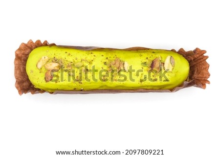 One green dessert covered with colored glaze. Decorated with nuts eclair isolated on a white background with a top view.