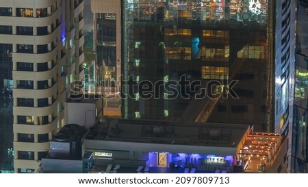Rooftop swimming pool viewed from above night timelapse. Aerial top view at financial district with illuminated skyscrapers. People relaxing. Dubai, UAE