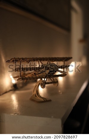Wooden airplane backlit by string of lightbulbs