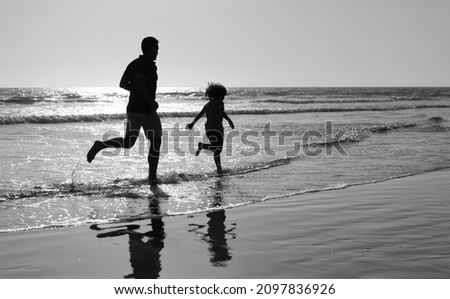 father and son silhouettes running having fun and feel freedom on summer beach, summer vacation