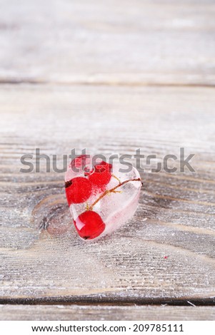 Ice cube with red currant, on wooden background