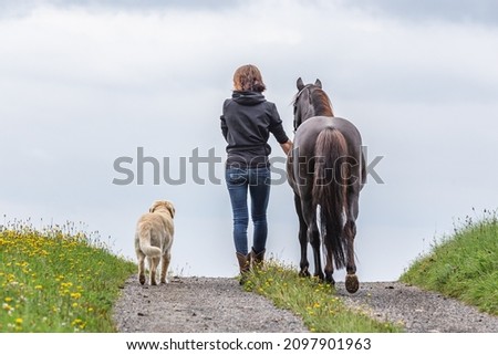 horse and dog team: Backside of a woman with her pony and dog Royalty-Free Stock Photo #2097901963