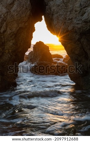 Sunstar in a sea cave in Malibu at sunset