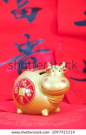 Year of the ox golden piggy bank on red background.The Chinese characters in the picture mean: "Lucky Strike"and"rich"　