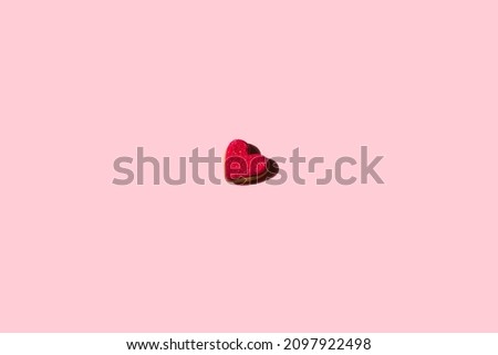 Red gingerbread heart with sugar on a pink background. Valentine's Day greetings in the style of minimalism. Romantic concept banner with space for text