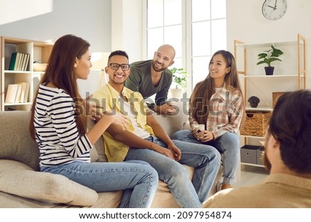 Diverse group of happy young friends having fun together. Smiling mixed race multi ethnic people talking and sharing interesting stories while sitting on the sofa at a friendly get-together at home Royalty-Free Stock Photo #2097954874