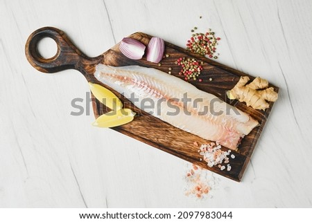 Top view of freshly frozen zander fillet on wooden cutting board Royalty-Free Stock Photo #2097983044