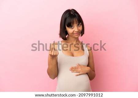Young pregnant woman over isolated pink background making money gesture