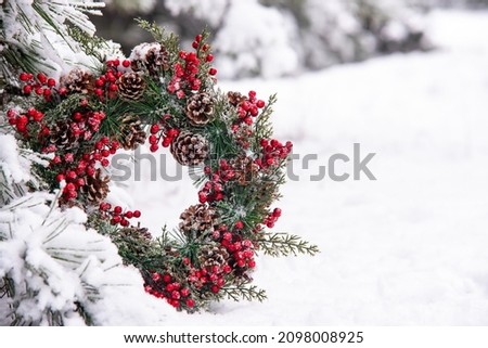 Beautiful christmas advent wreath with viburnum standing towards pine tree branches in the white snowy forest