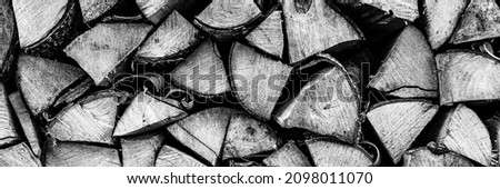 textured firewood background of chopped wood for kindling and heating the house. a woodpile with stacked firewood. the texture of the birch tree. toned in black white or gray color. banner
