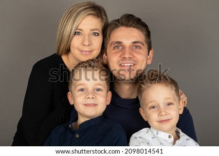 Happy family looking to the camera in front of grey background 