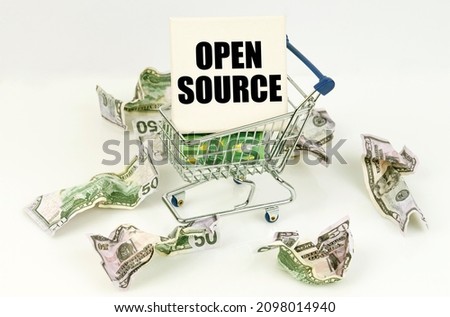 Business and economy concept. Crumpled dollars lie on a white surface, there is a cart inside a sign with the inscription - OPEN SOURCE