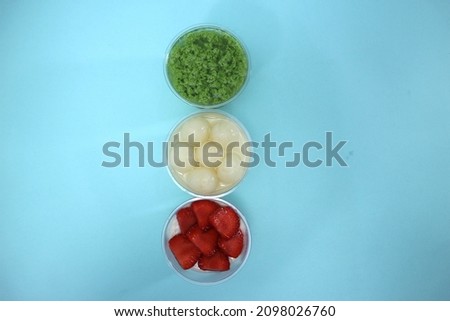Picture of homemade strawberry pudding, longan pudding and moss pudding in plastic cups, taken with top view angle, with blank space background for text, body text, or headline.