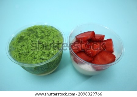Picture of homemade strawberry pudding and moss pudding or pandanus pudding in plastic cups.