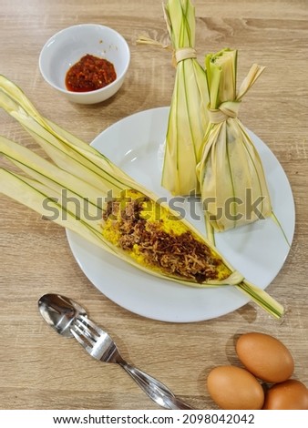Nasi Kuning Seroja,a traditional yellow steam rice from Manado, South Sulawesi, Indonesia. Served on young coconut leaves or daun lontar. With various dish specialty is served with fried cakalang fish Royalty-Free Stock Photo #2098042042