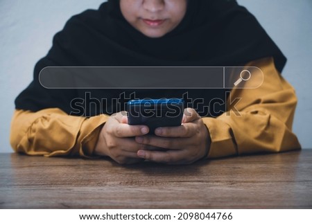 Data search concept. Search engine optimization SEO. A hijabi women looking for information through a mobile phone.