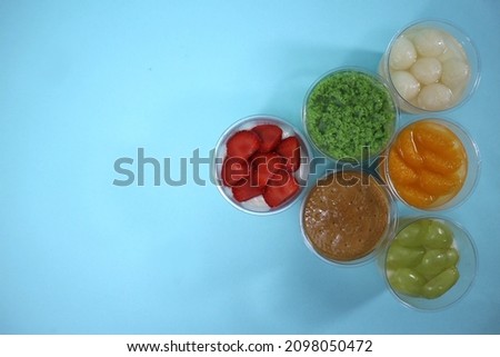 Jakarta, Indonesia, Dec 15, 2021, picture of six cups of homemade strawberry, orange, moss, longan, biscuit, and white grape pudding with blank space for text or text space or copy space or headline.