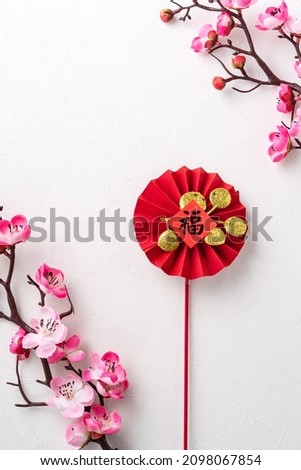 Top view of Chinese lunar new year background copy space design concept with pink plum blossom and festive decoration, the word inside picture means blessing.