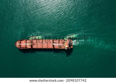 aerial top view tugboat pulling red oil ship to shipyard dry dock repairing and maintenance in green sea 