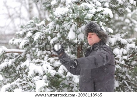 A man plays snowballs in a park during a snowfall