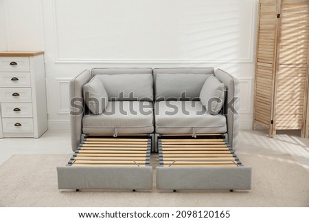 Stylish room interior with sleeper sofa near white wall. Additional place for guest Royalty-Free Stock Photo #2098120165