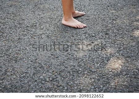 a pair of bare feet, on the asphalt road