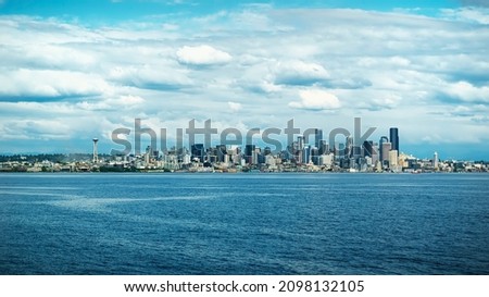 Stunning wide view of the beautiful cityscape of Seattle with the Space Needle, Skyscrapers, and the coastline from the point of view on a ferry on a warm cloudy summer day in Washington State, USA.