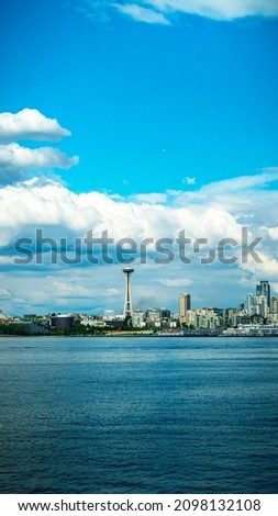 Stunning view of the beautiful cityscape of Seattle with the Space Needle, Skyscrapers, and the coastline from the point of view on a ferry on a warm cloudy summer day in Washington State, USA.