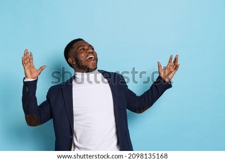 Wow emotions, One excited young stylish dark skinned man, student wearing white neck-polo and jacket isolated on navy color background. Facial expression, fashion, study, diversity concept.