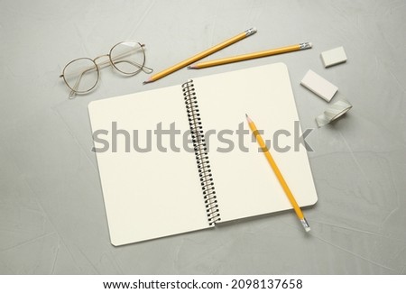 Flat lay composition with sketchbook, glasses and stationary on light grey table