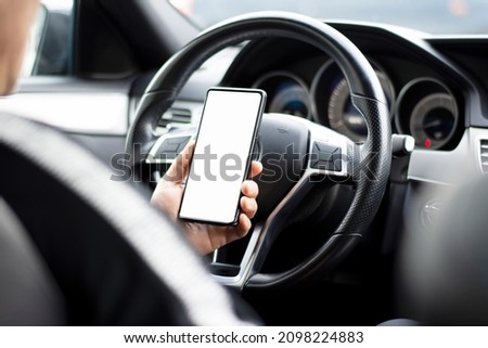 Male hands holding phone with isolated screen behind wheel in car Royalty-Free Stock Photo #2098224883