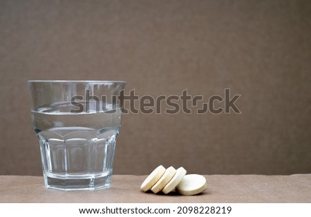 A glass glass with water and three aspirin tablets. Taking medications. a clean background for the text. Prescribing medications.