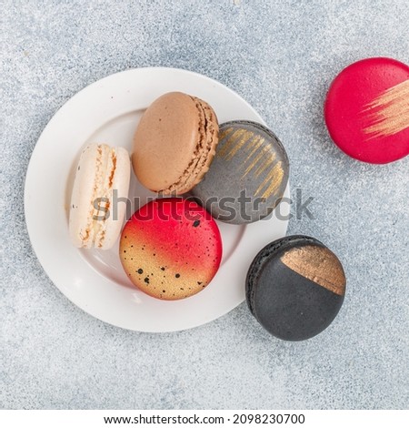 Assorted multicolored macaroon cookies on a gray concrete background close-up. Sweet French macarons biscuits. Desert for gourmets. Selective focus, top view, copy space,  square picture