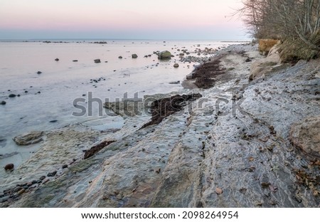 Scenic view to the coastal  limestone terrace cliff formations with the sunset colored sea and sky background