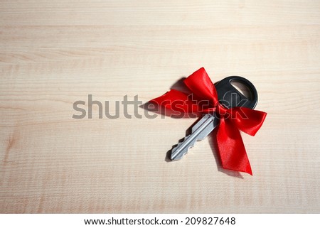Car key with colorful bow on wooden background