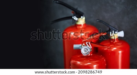 Three red fire extinguishers on a dark background with the space for text. 