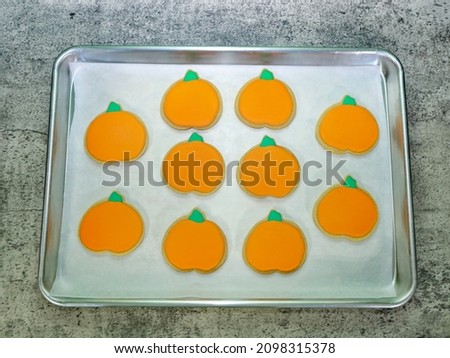 Pumpkin sugar cookies with royal icing on a baking pan.